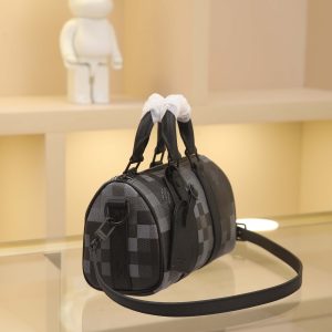 Alternative view of Keepall Bandoulière 25 bag crafted from Damoflage Black coated canvas, vividly reimagining the Damier Graphite pattern through Pharrell Williams' creative vision. The iconic check pattern takes on a pixelated effect, while deep tones create a distinctive camouflage aesthetic. Top handles and a removable, adjustable shoulder strap offer versatile carrying options. Dimensions: 25×15×11cm